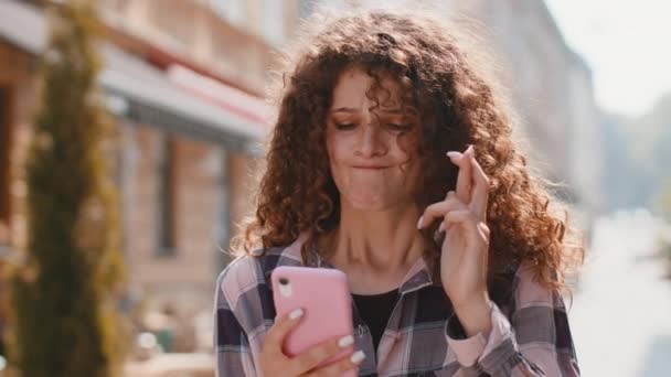 漂亮的年轻女人用智能手机打字浏览 失去了成为惊喜突然彩票结果 坏消息 财富损失 女孩走在城市阳光城市的大街上 城镇生活方式 — 图库视频影像