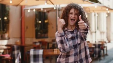 Gibi. Mutlu genç bir kadın kameraya onaylayıcı bir şekilde bakıyor, olumlu bir geri bildirim imzalıyor gibi. Şehir Güneşi Sokağı 'nda yürüyen bir kız. Şehir yaşam tarzları açık havada