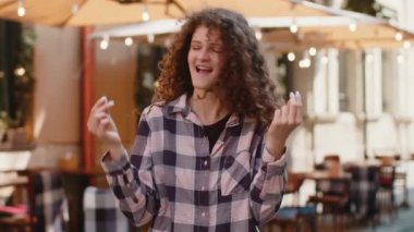 Neşeli, zengin, genç ve güzel bir kadın el hareketleriyle etrafa para saçıyor, daha fazla bahşiş, daha fazla kar, piyango kazanmak, paylaşmak, kutlamak. Şehir merkezinde gezen bir kız.