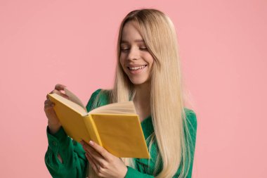 Mutlu beyaz kadın komik bir masal kitabı okuyor, hobi, bilgi, bilgelik, eğitim, öğrenme, çalışma. Genç gülümseyen kız pembe stüdyo geçmişinde izole edilmiş.
