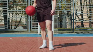 Spor giyimli genç Lübnanlı adam basketbol oynuyor. Şehir sahasında top süren atletik bir adam. Spor sahasında spor rutini. Egzersiz, egzersiz, antrenman. Güneşli bir sabahta açık havada