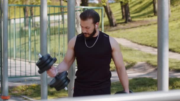 スポーツウェアのアスレチックレバノン人男性腕の重さを行うダンベル演習を持ち上げ 腕の両足の筋肉を汲み上げます 遊び場の若い男 スポーツ フィットネスルーチン ワークアウト 強みの動機 — ストック動画