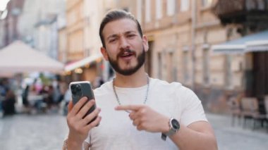 Sakallı genç adam cep telefonuyla kutlama yapıyor. İyi haber kazan, piyango zaferi kazan, açık havada dağıtım yap. Şehir Güneşi Şehri caddesinde yürüyen mutlu bir turist. Kasaba yaşam tarzları