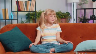 Havalı, neşeli, pozitif sarışın kız dans ediyor, ritme ayak uyduruyor, el kaldırıyor, dublaj yapıyor. Gündüz vakti evde oturan çocuk kanepede oturuyor.