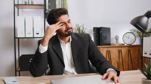 Tired indian businessman feeling worried about financial problem, stress at home office workplace. Indian freelancer broker man frustrated thinking of money debt, budget loss, bankruptcy. Overworking