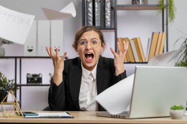 Stresli genç iş kadını ödenmemiş banka borçlarına bakıyor, evrak işleriyle uğraşıyor, bütçe planlıyor, ev kredisi ödemelerini hesaplıyor. Hoşnut olmayan serbest çalışan kız kağıt para atıyor.