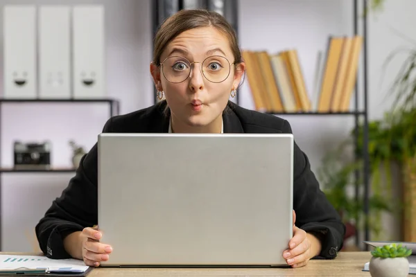 白种人快乐的女商人躲在笔记本电脑后面做着滑稽的脸 鬼鬼祟祟 在办公室里远程工作 不尊重别人 专业自由职业女孩 — 图库照片