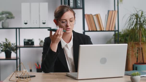 stock video Caucasian young business woman working, having mobile phone loudspeaker talk at office desk with laptop. Manager freelance girl holding smartphone using messenger chat apps. Employment, occupation