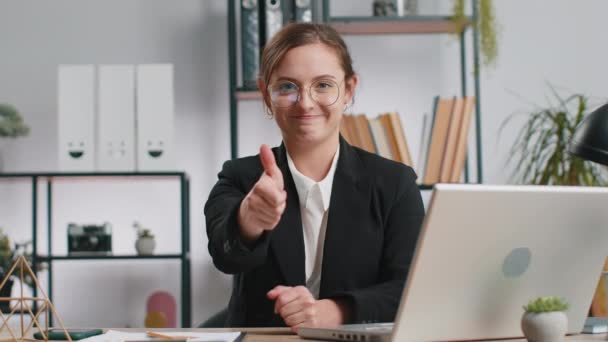 快乐的白人女商人在笔记本电脑上工作时 赞许地看着展示大拇指的相机 就像在办公室里签积极正面的东西 积极的反馈 自由职业者女孩 — 图库视频影像