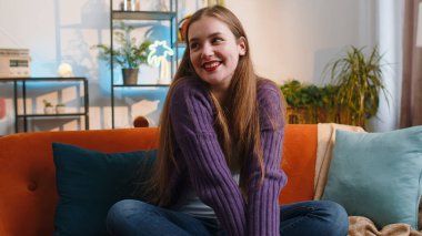 Portrait of happy calm young woman at home couch smiling friendly, glad expression looking away dreaming resting, relaxation feel satisfied concept good news, celebrate win. Girl on living room sofa