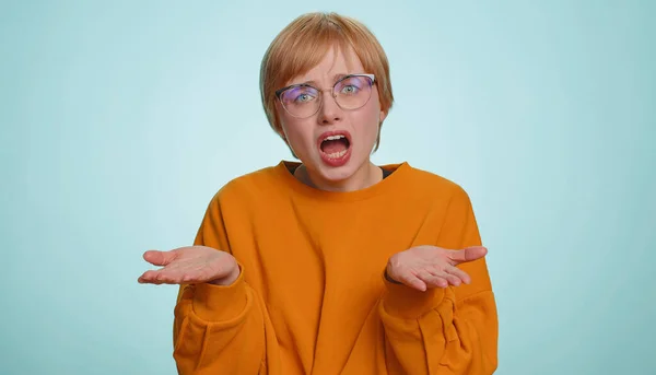 What Why. Sincere irritated woman in glasses raising hands in indignant expression, ask reason of failure demonstrating disbelief irritation by trouble. Pretty confused blonde girl on blue background