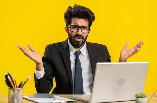 失敗の理由を尋ねる不満インドのビジネスマン 結果に失望退屈不信刺激感を表現 オフィスの職場で悪いニュース ヒンズー教徒男でフォーマルスーツ作業上のラップトップ — ストック写真