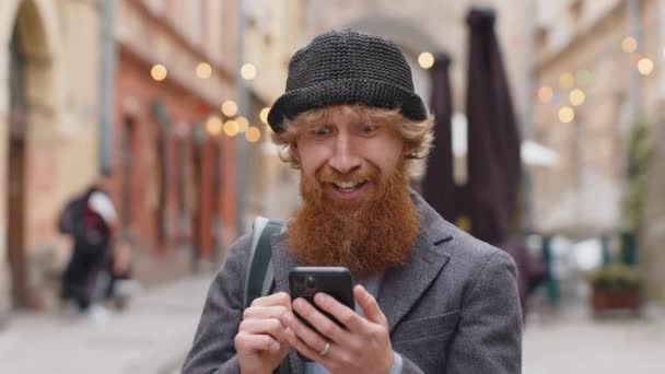 Bărbatul Barbă Tânără Folosește Smartphone Mobil Care Sărbătorește Câștigarea Știrilor — Videoclip de stoc