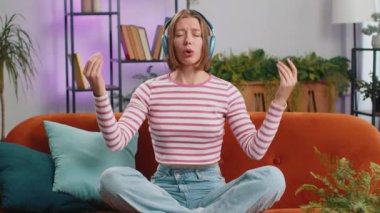 Sakin ol, rahatla, iç denge. Esmer kadın derin nefes alıyor Mudra jesti, gözleri kapalı, konsantre düşüncelerle meditasyon yapıyor, evinde huzurlu bir zihin. Kanepede oturan kız