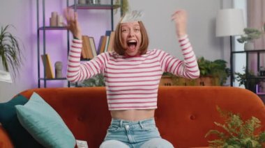 Kazanan, başarıyı kutlayan, gol atan, iyi haber, piyango talihi, evdeki hayaller gerçek oluyor. Kariyer büyür. Kanepede oturan esmer kız.