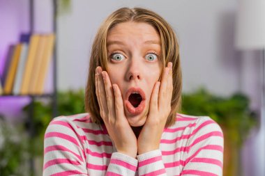 Aman Tanrım, vay canına. Esmer genç kadın kameraya büyük gözlerle bakarken şaşırdı. Ani bir zafer, iyi bir galibiyet haberi, evde kutlama. Oturma odasında kanepede oturan heyecanlı kız.