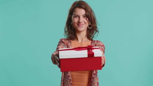 正面面带微笑的年轻女子献上生日礼物盒 伸出手来 提供包装好的职业奖金 庆祝派对 布鲁内特女孩孤身一人 背景为蓝色 — 图库视频影像
