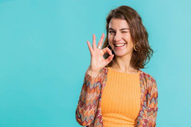 - Tamam. Neşeli, mutlu, genç bir kadın onaylayıcı bir şekilde kameraya bakıyor. Onaylanmış geri bildirim jesti yapıyor. Güzel kız mavi arka planda izole edilmiş. İnsanlar samimi duygular