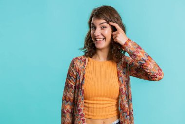 You are crazy, out of mind. Displeased woman pointing at camera, show stupid gesture finger near head, blaming some idiot for dumb insane plan idea, senseless talk. Girl isolated on blue background