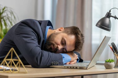 Sıkıcı, uykulu, Kafkasyalı iş adamı dizüstü bilgisayarda çalışıyor, ev ofisinde uyuya kalıyor. Yorgun, serbest çalışan, işkolik genç bir adam. İstihdam, meslek, işsiz
