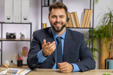 Kafkasyalı iş adamının kulaklık takan POV portresi, serbest çalışan çağrı merkezi veya destek servis operatörü yardım hattı, ofiste müşteri veya iş arkadaşlarıyla hoş sohbetler yapmak