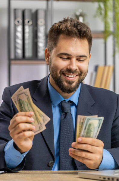 Rich businessman working on laptop counting money cash, calculate earnings income profit at home office workplace. Professional manager freelancer man. Business people. Employment occupation. Vertical