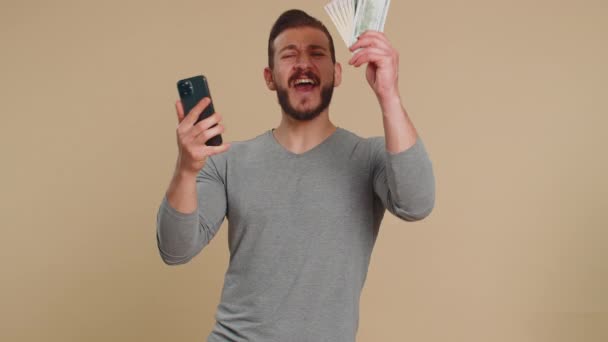 黎巴嫩男子期待智能手机展示真诚喜悦的胜利 收到钞票钞票 成功彩票头彩好运 收入薪水工资 带着米色背景的中东人 — 图库视频影像