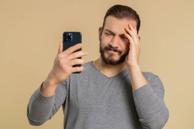 Lübnanlı adam cep telefonuna yazarak arama yapıyor. Aniden piyango sonuçları, kötü şans, kayıp, başarısızlık şaşkınlığını kaybediyor. Yakışıklı orta doğulu adam bej renkli stüdyo arka planında kapalı alanda izole edilmiş.