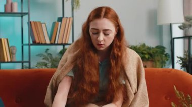 Hasta, genç, kızıl saçlı, tıbbi vitamin hapı alan, bir bardak su içen bir kadın. Sağlık ve tıbbi yaşam tarzı hastalığı, diyet zayıflama konsepti. Evdeki kız kanepede oturuyor.