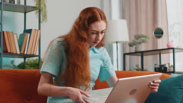 不高兴的女人用笔记本电脑打字上网工作 突然失掉了意想不到的彩票结果坏消息运气损失失败了电脑病毒 红头发姑娘在家里沙发上的房间里 — 图库视频影像