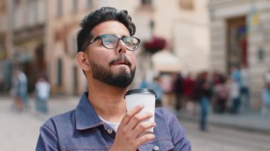 Genç sakallı Hintli adam sabah kahvesini ya da sıcak çayını dışarıda içiyor. Dinleniyorum, ara veriyorum. Şehir merkezi caddesinde yürüyen Hintli adam, gitmek için kahve içiyor. Dışarıdaki kasaba yaşam tarzları