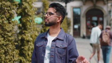 Alışveriş sonrası alışveriş yapan mutlu, genç, yetişkin Hintli adam dışarıda hediyelerle dolu poşetlerle. Hintli turist şehir caddesi boyunca yürüyordu. Kasaba yaşam tarzları