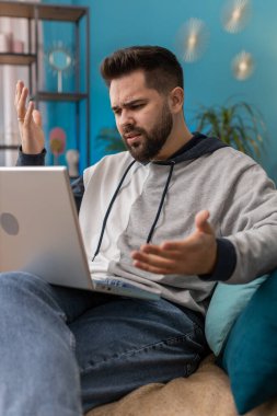 Hoşnut olmayan beyaz adam dizüstü bilgisayar kullanıyor. Daktilo çalışıyor. Aniden piyangoyu kaybediyor. Evdeki genç adam kanepede yatıyor.