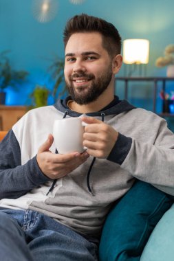 Sabahları bir fincan sıcak kahve ya da bitki çayı içen gülümseyen sakallı adamın portresi. Kafkasyalı bir adam evinde kanepede dinlenerek rahatlıyor. Dikey