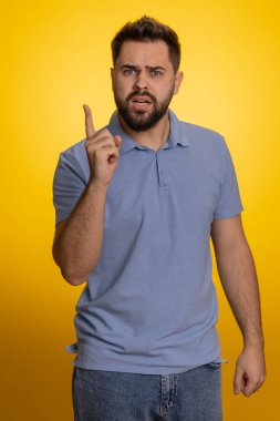 Tartışma. Sinir bozucu ve hoşnutsuzlukla el kol hareketi yapan, başarısızlıktan dolayı azarlayan, bunun neden olduğunu soran genç, beyaz bir adam. Sakallı yetişkin adam sarı stüdyo arka planında izole edilmiş.