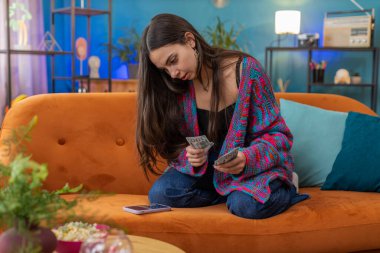 Planlama bütçesi. Zengin, mutlu, genç bir kadın nakit sayıyor. Akıllı telefon hesap makinesi uygulaması kullanıyor ve ev faturalarını hesaplıyor. Gelir getiren, kazanan, planlı tatil için para biriktiren, hediyeler alan bir kız.