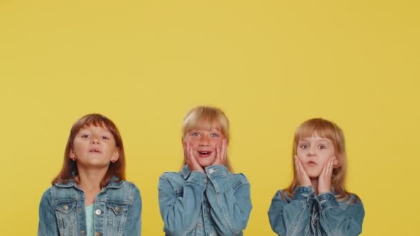 10代の女の子 小さな子供の姉妹が親指を上げて空の場所 商業テキストの広告エリア 商品プロモーションのためのコピースペースを指しています スタジオで3人の兄弟子供黄色の背景 — ストック動画