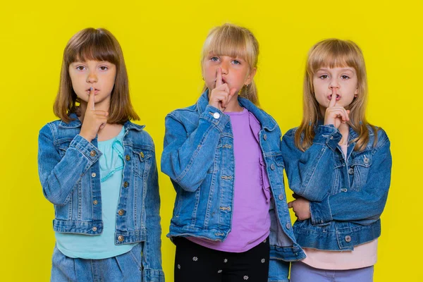 请安静 少女可爱的女孩把食指按在嘴唇上 使沉默手势不泄密 孩子们的妹妹三个兄弟姐妹的孩子被隔离在工作室的黄色背景下 — 图库照片