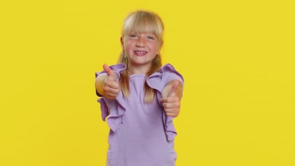 快乐的十几岁以下的小女孩高兴地看着摄像机露出大拇指 喜欢签署积极的东西好的 积极的反馈好消息 在工作室黄色背景下被隔离的儿童 — 图库视频影像