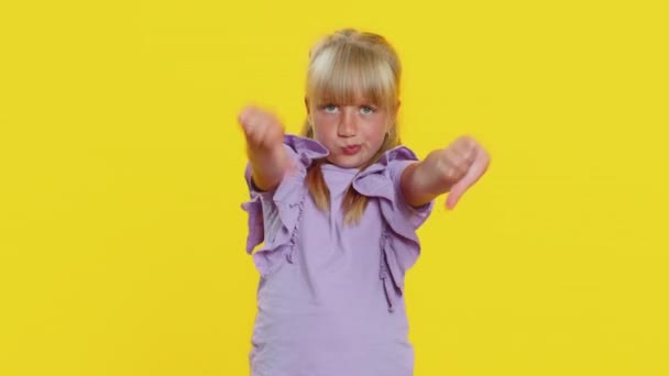 不喜欢 心烦意乱的十几岁以下的小女孩表现出大拇指垂下的手势 表达不满 不赞成 不满意的恶劣工作 不喜欢黄色工作室背景的可爱孩子 — 图库视频影像