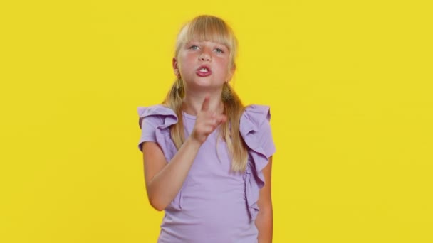 请安静 十几岁以下的女孩把食指按在嘴唇上 使沉默沉默的手势不泄露秘密 在工作室黄色背景下孤身一人的可爱小孩 — 图库视频影像
