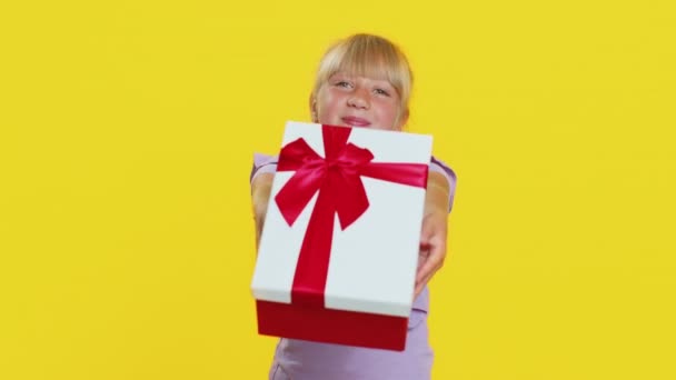 可爱的微笑着的十几岁以下的小女孩献上生日礼物盒 伸出手来 提供包装好的职业奖金 庆祝派对 工作室黄色背景上可爱的小朋友 — 图库视频影像