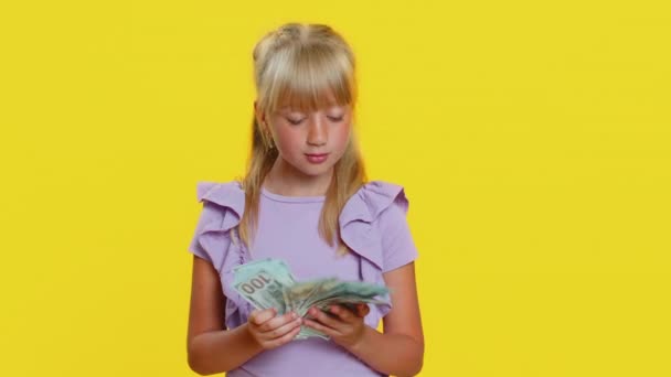 富人很高兴年轻可爱的女学生挥动钞票 像扇子一样的钞票 彩票中奖 丰厚的收入 工作室黄色背景上的年轻金发女孩 — 图库视频影像
