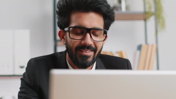 インド人の髭を生やしたビジネスマンが ラップトップコンピュータで働いている自宅のオフィスでフリーランスに直面しています マネージャーフリーランスインド人男性はノートブックの送信メッセージに取り組んでオンライン購入を行います — ストック動画
