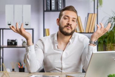 I dont know what to say. Confused business man working on laptop at office workplace. Freelancer feeling embarrassed about ambiguous question, having doubts, no answer idea, being clueless, uncertain