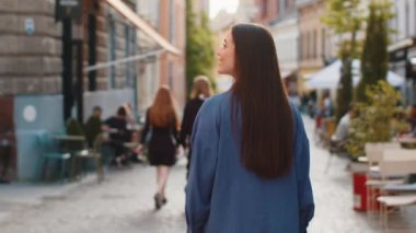 Genç yetişkin kadın turistin Avrupa sokaklarında gezinip bir yol aradığı arka manzara. Şehir arka planında gezen güzel bir kız gezginin arka görüntüsü. Kasaba yaşam tarzları
