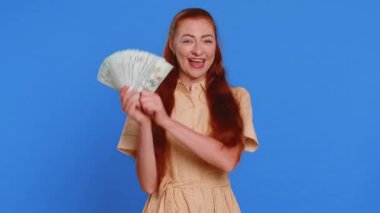 Zengin, genç bir patron, hayranı, başarılı bir iş adamı, piyango talihlisi, büyük gelir ve servet gibi banknotlar sallıyor. Kızıl saçlı yetişkin kız mavi arka planda, kapalı alanda izole edilmiş.