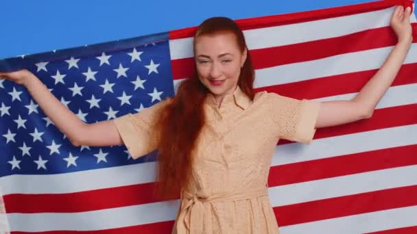 若い成人女性は アメリカの国旗を振り 自由を表します 独立記念日 屋内青いスタジオの背景に隔離されたかなり魅力的な白人少女 — ストック動画