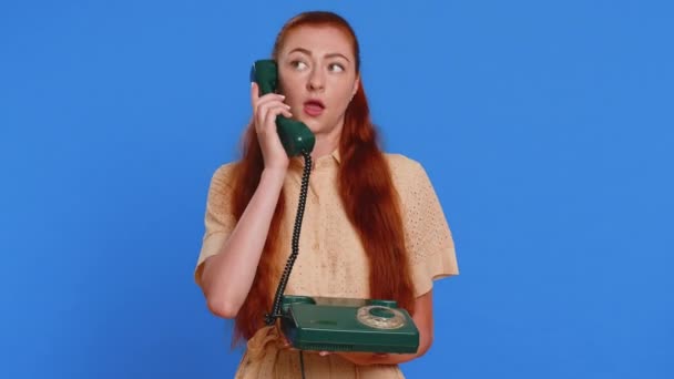 若い大人の疲れた眠っている女性は 友人と80代の有線ヴィンテージ電話で話し 会話をしました 青いスタジオの背景で孤立した退屈なトークをしている興味深い赤毛の少女 — ストック動画