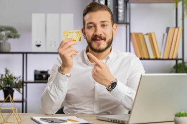 İş adamı, kredi kartı reklamlarını, nakit para transferlerini, online alışverişleri, indirimleri, internet siparişlerini, rezervasyonları gösteriyor. Serbest çalışan adam kameraya bakıyor.